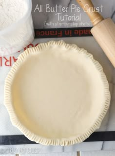 an uncooked pie crust sitting on top of a table next to a rolling pin