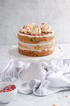 a cake with white frosting and sprinkles sitting on top of a plate