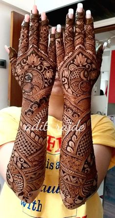 a woman is holding her hands up with henna tattoos on it