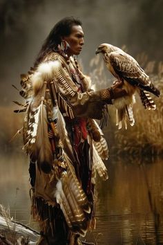 a native american man holding a bird in his hand and standing next to water with reeds