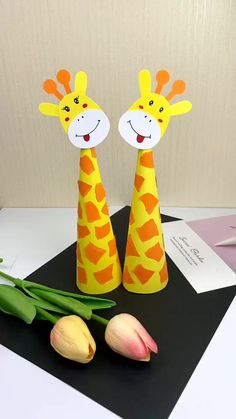 two paper giraffes are standing next to tulips on a table