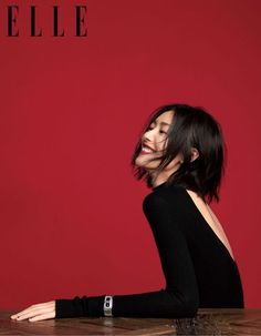 a woman sitting at a table in front of a red wall