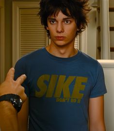 a young man in a blue shirt giving the thumbs up sign with his right hand