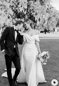 a bride and groom standing in the grass