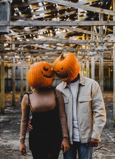 a man and woman wearing pumpkins on their heads walking through an abandoned warehouse area