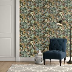 a blue chair sitting in front of a wall with a flowered pattern on it