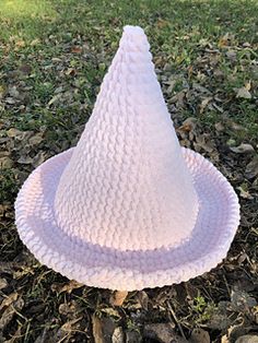 a white plastic hat sitting on top of a pile of leaves next to a tree