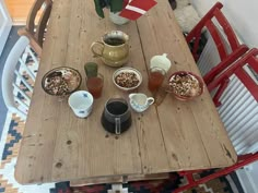 a wooden table topped with bowls of food and cups of coffee on top of it