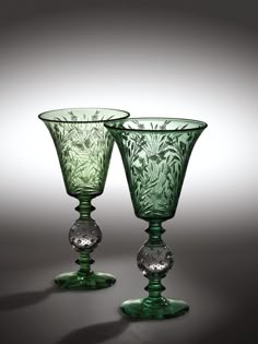 two green glass goblets sitting next to each other on a gray tablecloth