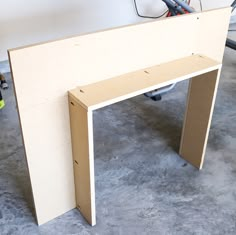 an unfinished table is sitting on the floor next to a workbench and tools