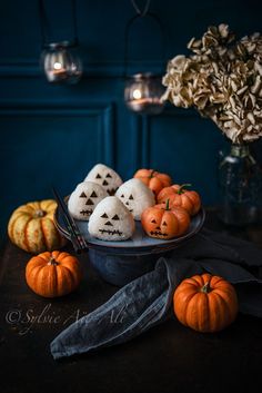 some pumpkins are sitting in a bowl on a table next to other small pumpkins