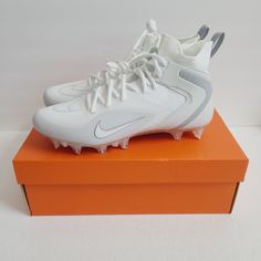 a pair of white nike cleats sitting on top of an orange shoe box