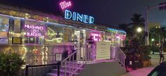 the diner is lit up at night with neon lights on it's windows and stairs