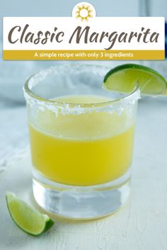 a close up of a drink in a glass on a table with limes around it