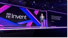 a man standing on top of a stage in front of a sign that says aws re inventt