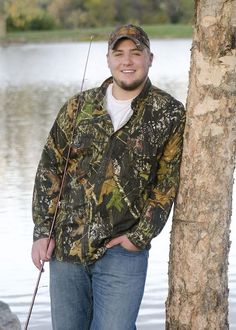 a man standing next to a tree holding a fishing pole