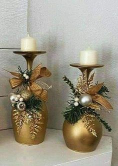 three gold vases with christmas decorations and candles on top of a white shelf next to a wall