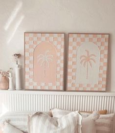 two pink and white paintings on the wall above a bed with pillows, vases and flowers