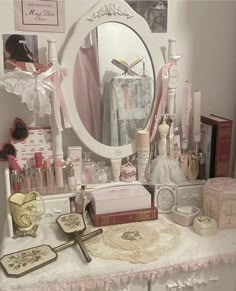 the vanity is covered in pink and white accessories, such as perfumes, books, and other personal care items