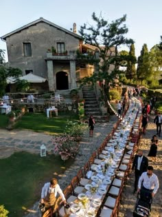 a long table is set up in front of a house with people standing around it