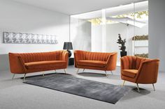 an orange couch and two chairs in a living room with a rug on the floor