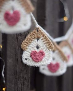 crocheted ornaments hanging from a wooden fence with lights in the background and hearts on them