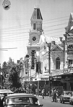 an old black and white photo of cars driving down the street