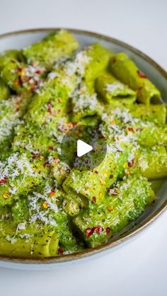 a bowl filled with green vegetables covered in parmesan sprinkles and seasoning