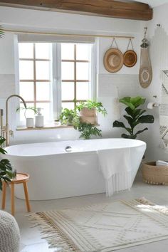 a white bathroom with plants and rugs on the floor