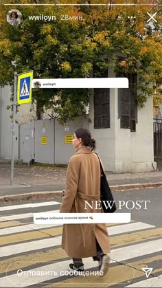 a woman walking across a cross walk in front of a building