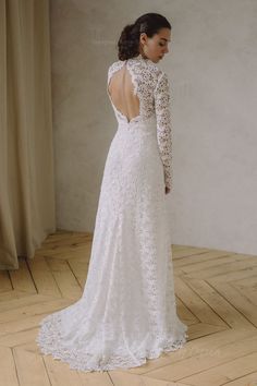 a woman in a wedding dress standing on a wooden floor looking back at the camera