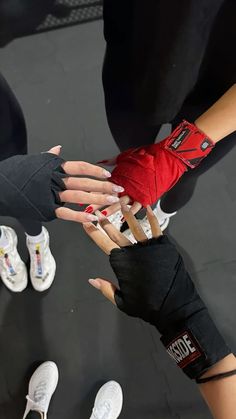 two hands with red gloves on each hand and white tennis shoes in the back ground