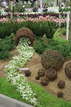 an outdoor garden with various plants and flowers in the center, including straw ball sculptures