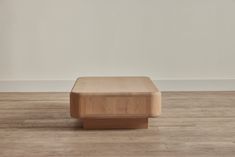 a wooden bench sitting on top of a hard wood floor next to a white wall