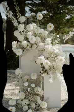 a white vase with flowers in it sitting on the ground