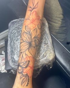 a woman's foot with flowers and butterflies on her left leg, in front of a car