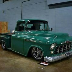 an old green truck parked in a garage