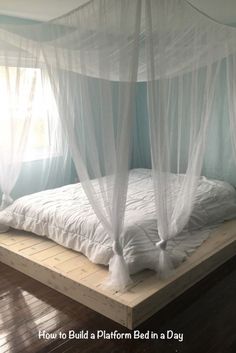 a bed with white mosquito netting on it in a room that has hardwood floors and blue walls