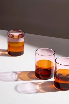 three glasses filled with liquid sitting on top of a white table next to each other