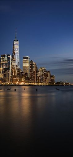 the city skyline is lit up at night, with skyscrapers in the foreground