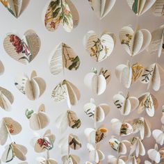 paper hearts hanging from the ceiling with flowers and leaves on them, all made out of book pages