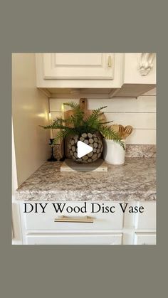 a kitchen with white cabinets and marble counter tops, including a vase filled with plants