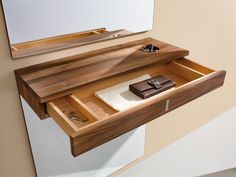 a bathroom vanity with a mirror and wooden drawer on the wall above it that is open