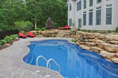 a backyard with a swimming pool and stone steps leading up to the side of the house