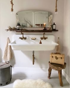 a white sink sitting under a bathroom mirror next to a trash can and luggage bag