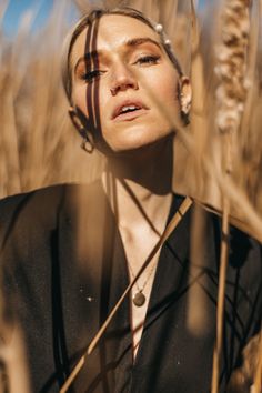 a woman standing in tall grass with her eyes closed and head tilted to the side