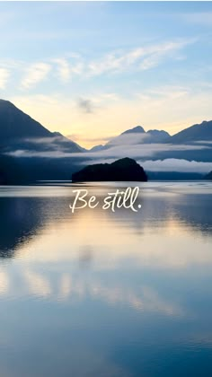 a lake with mountains in the background that says be still