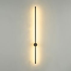 a wall mounted light on the side of a white wall with a black pole in front of it