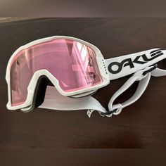 a pair of ski goggles hanging on a wooden surface with pink tinted lenses