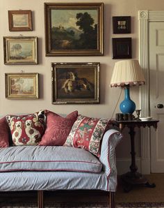 a living room filled with furniture and paintings on the wall